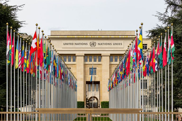 Palais des Nations Unies à Genève avec les drapeaux du monde — français diplomatique
